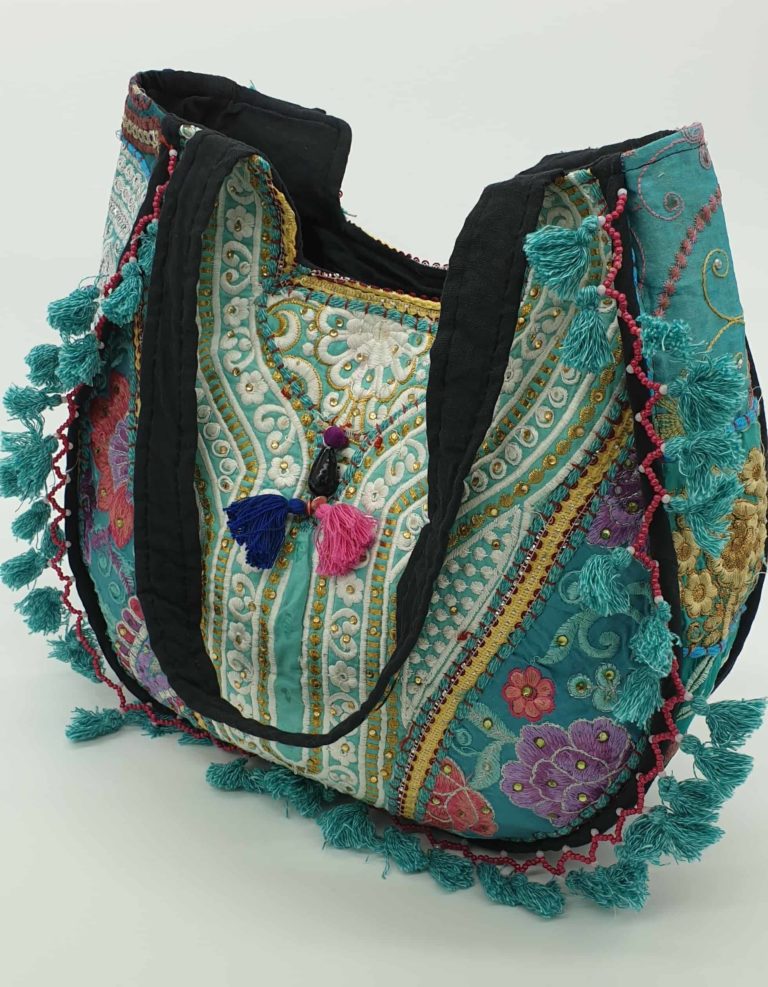 Patchwork hippy bag in teal blue with unique embroidery and a tassel trim. Fully lined with an embroidered black strap and floral panels.