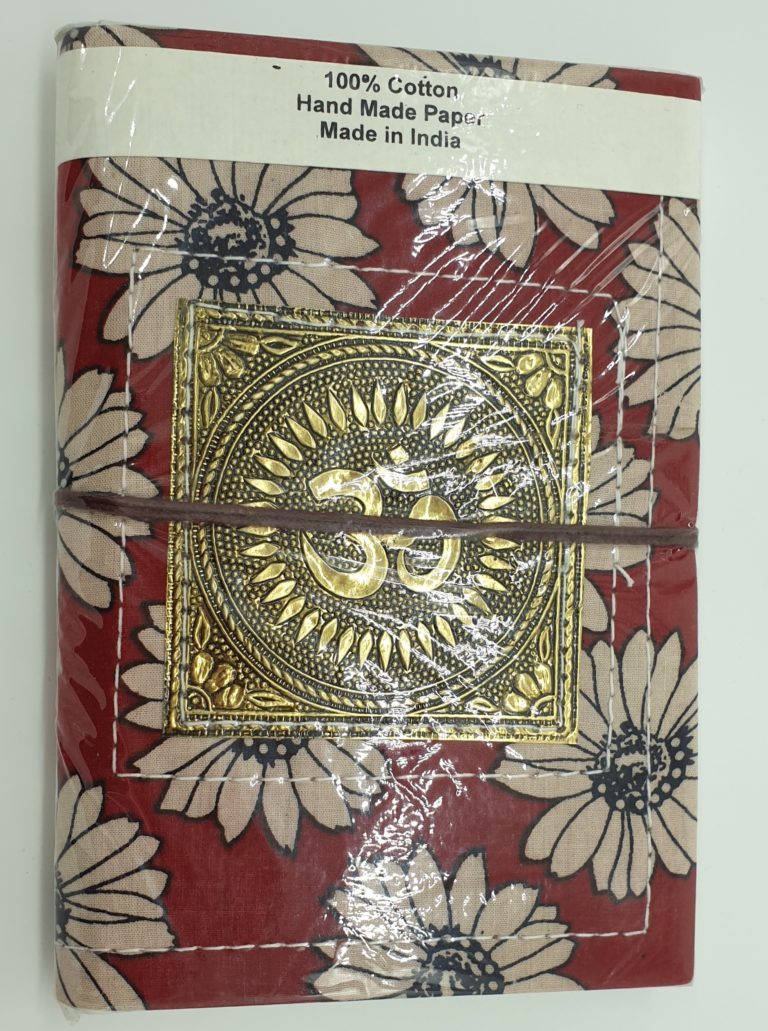 Handmade paper notebook with a stamped metal om on a floral fabric background. Plain paper pages and a tie. Make wonderful artistic gifts for creative people