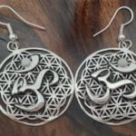 Round sterling silver om symbol earrings on a divine geometry flower of life background. Hung on fish hook ear wires.