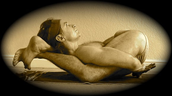 Yoga teacher interview with Ervin Menyhart. This image shows him in a difficult asana with his legs behind his head.