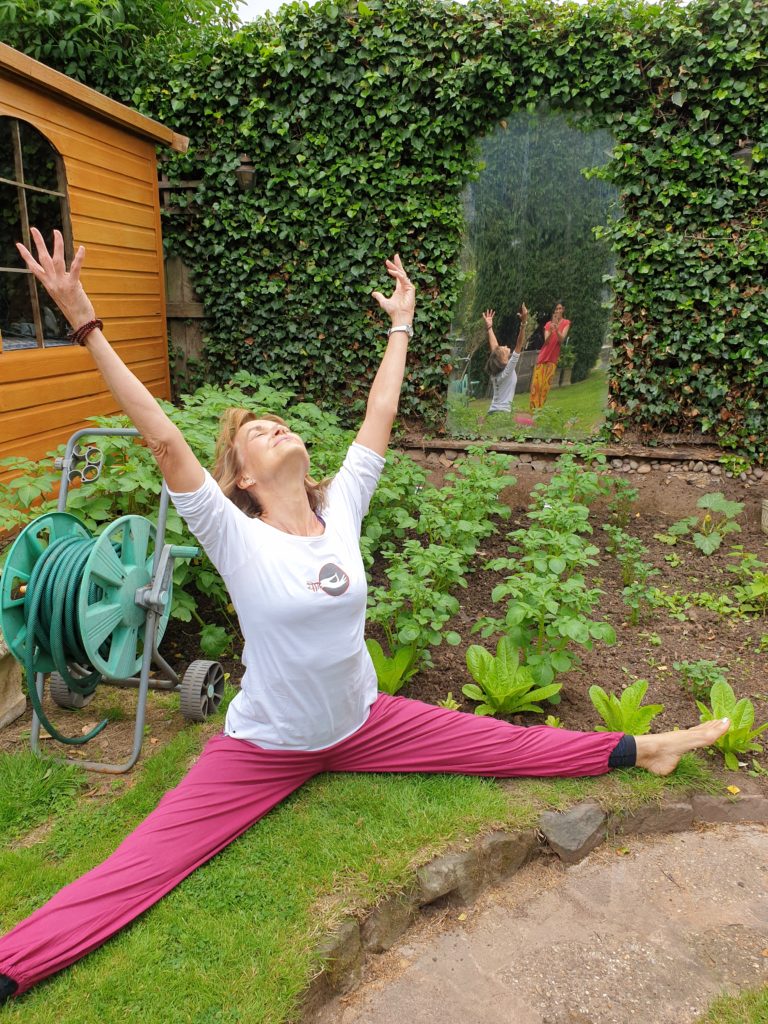 Yoga teacher maureen demonstrating a little yoga in the garden, aligning herself with the garden path.