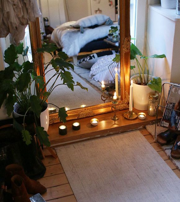 Beautiful yoga room with a large mirror and lit candles, surrounded by house plants on a wooden floor