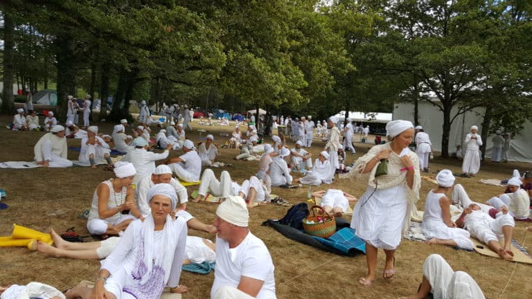 3ho kundalini yoga festival. A large group of kundalini yogis dressed in white gather in a field