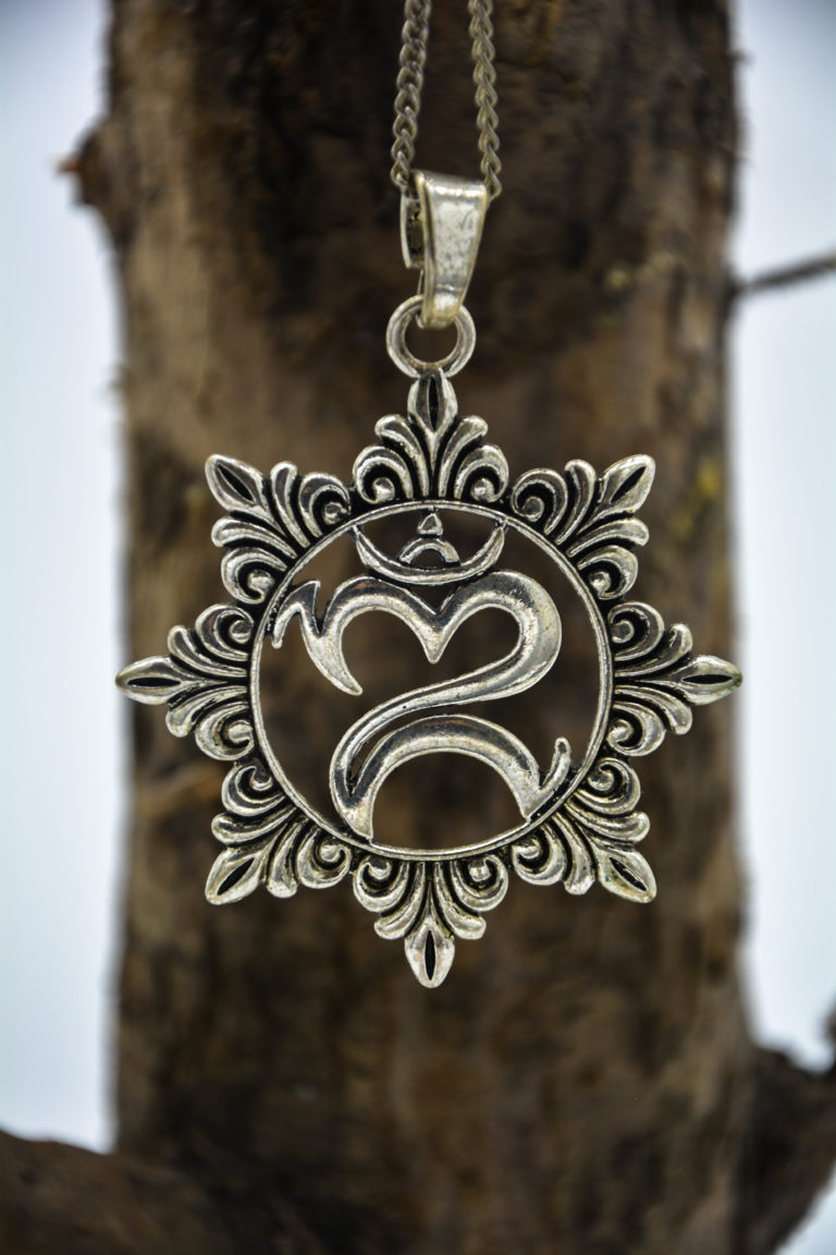Silver metal om symbol pendant with engraved flower petals around it.