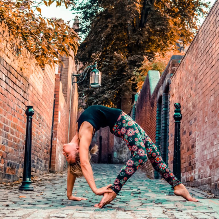 One of our best Yoga outfits modeled by a yoga teacher in a victorian cobbled alley. A black yoga top with mandala print red and black leggings.