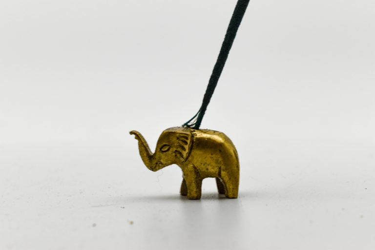 A bronze mini elephant statue with an incense stick in one of the drilled holes on top.