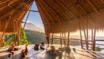 One of the amazing yoga studios in bali with a straw roof and open sides made of wood on a mountain by the sea