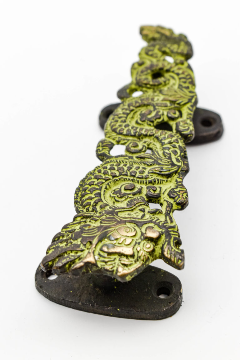 Nepalese dragon door handle. A piece of spiritual decor with a dragon motif. A carved bronze door handle with a green patina.