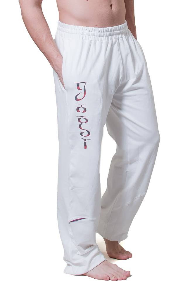 white yoga pants for men shown from the front with the term Yogi hand painted down the front leg. the model has his hands in the side pockets and the wide waist band is worn low