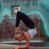 A model doing an elbow stand in front of a water fountain wearing blue organic yoga leggings