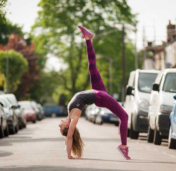 A model doing a back bend in pink organic yoga leggings from the yogamasti yoga leggings sale on a sunny street