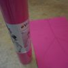 Yogamasti Pink Alignment non slip yoga mat shown in it's clear packaging next to an open version