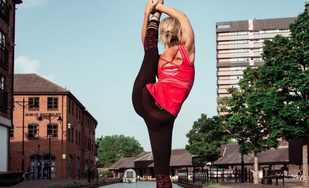 A yoga teacher doing standing splits by the coventry canal basin in our best seamless yoga leggings in black