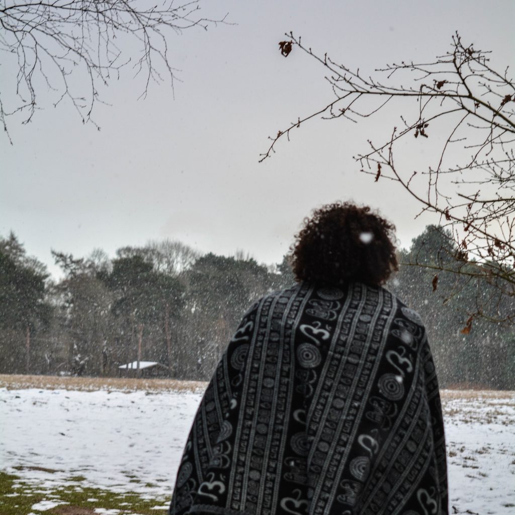 A model walks in the snow with shawl on, back to the camera. To illustrate the isolating feeling of the new year blues